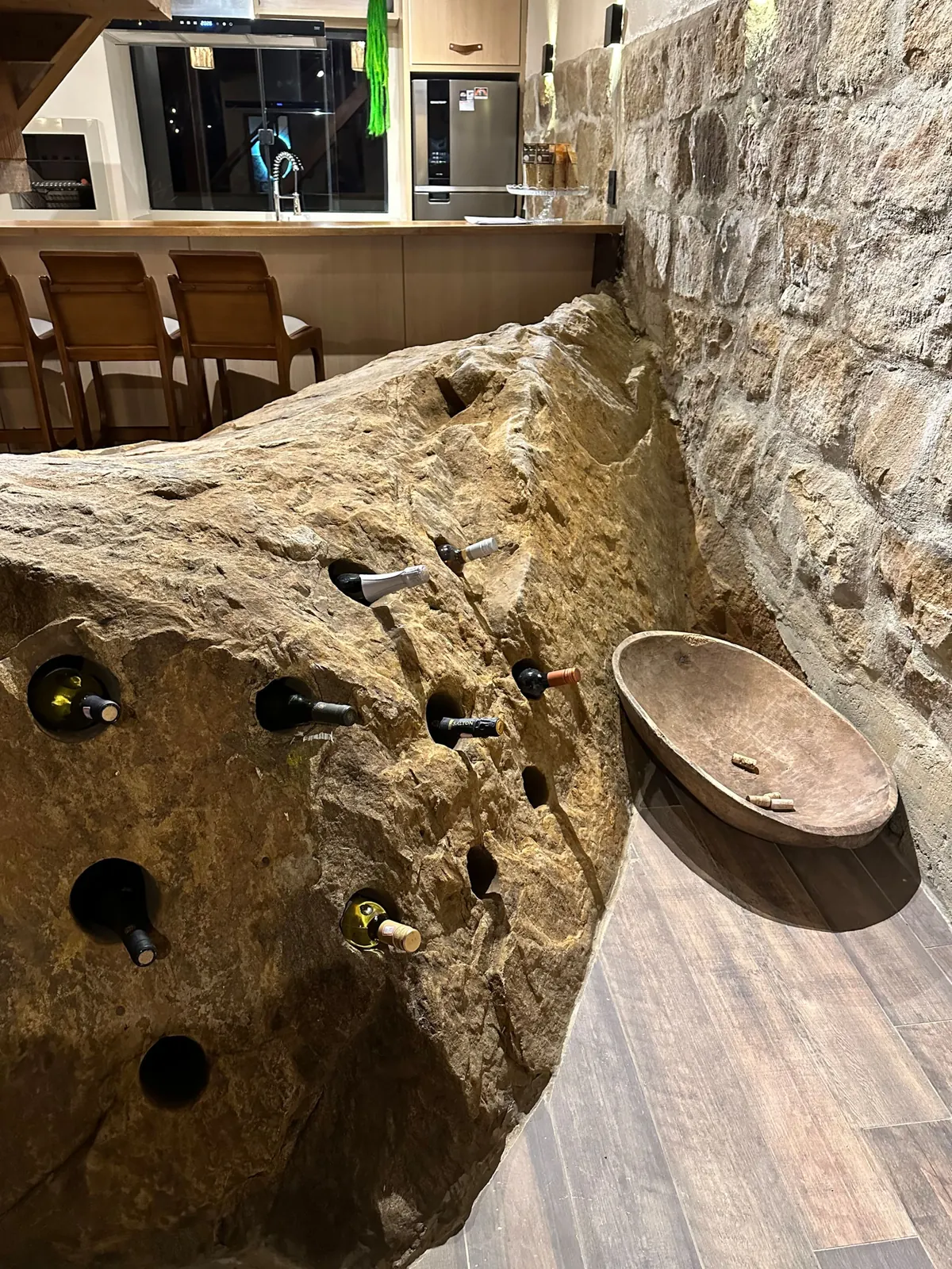 Garrafas de vinho encaixadas nos furos da pedra natural dentro da casa