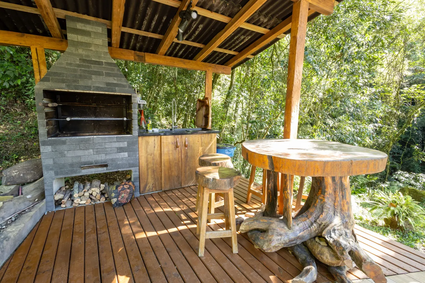 Churrasqueira externa com mesa de tronco no deck