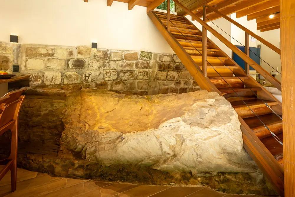 A pedra natural atravessando a sala até a escada