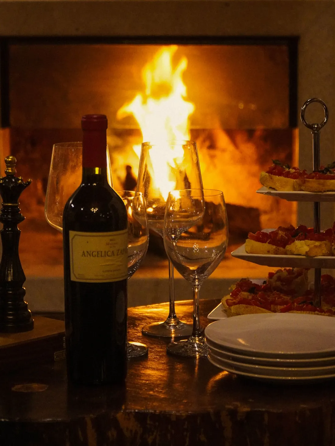 Vinho e taças em frente à lareira
